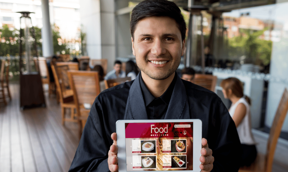 Hombre mostrando el menu en su pagina web desde su tablet
